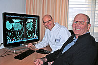 Medizinischer Meilenstein in OWL: 20 Zentimeter großer Lebertumor erstmals mit dem DaVinci-Roboter im EvKB entfernt Univ.-Prof. Dr. med. Jan Schulte am Esch und Claus Diekmann, am Rechner im HIntergrund sind Untersuchungsbilder der Leber zu sehen.