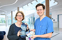 Ein Zeichen der Wärme und Verbundenheit für junge Patienten Kraftvolles Zeichen: Katja Stern übergibt die Socken an Dr. Jeremy Schmidt; Foto: Manuel Bünemann
