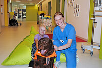 Therapiehund in der Kinderonkologie: „Mit Ellie macht einfach alles mehr Spaß“ Bild von Therapiehund Ellie, die Besitzerin und einer kleiner Patientin.