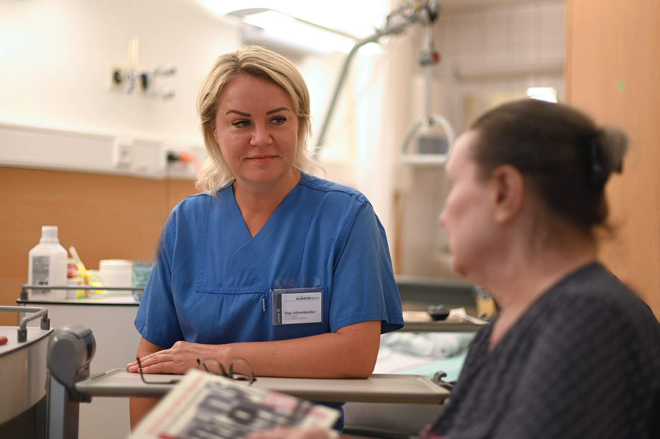 Geriatrie Gespräch zwischen Pflegekraft und Patientin im Patientenzimmer.