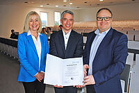 Notfallmedizin: Neue wissenschaftlich-ärztliche Leitung an Rettungsdienstschule Drei Personen auf dem Bild. In der Mitte Prof. Dr. Rehberg, hält die Bestellungsurkunde in der hand.